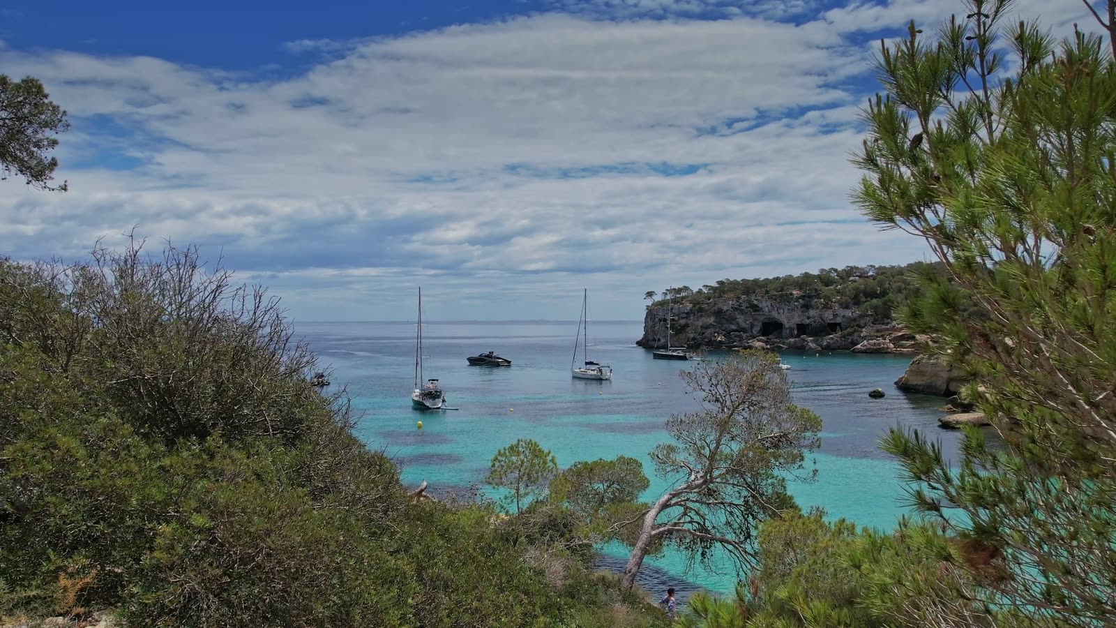 Cala mediterránea de aguas turquesas con barcos fondeados