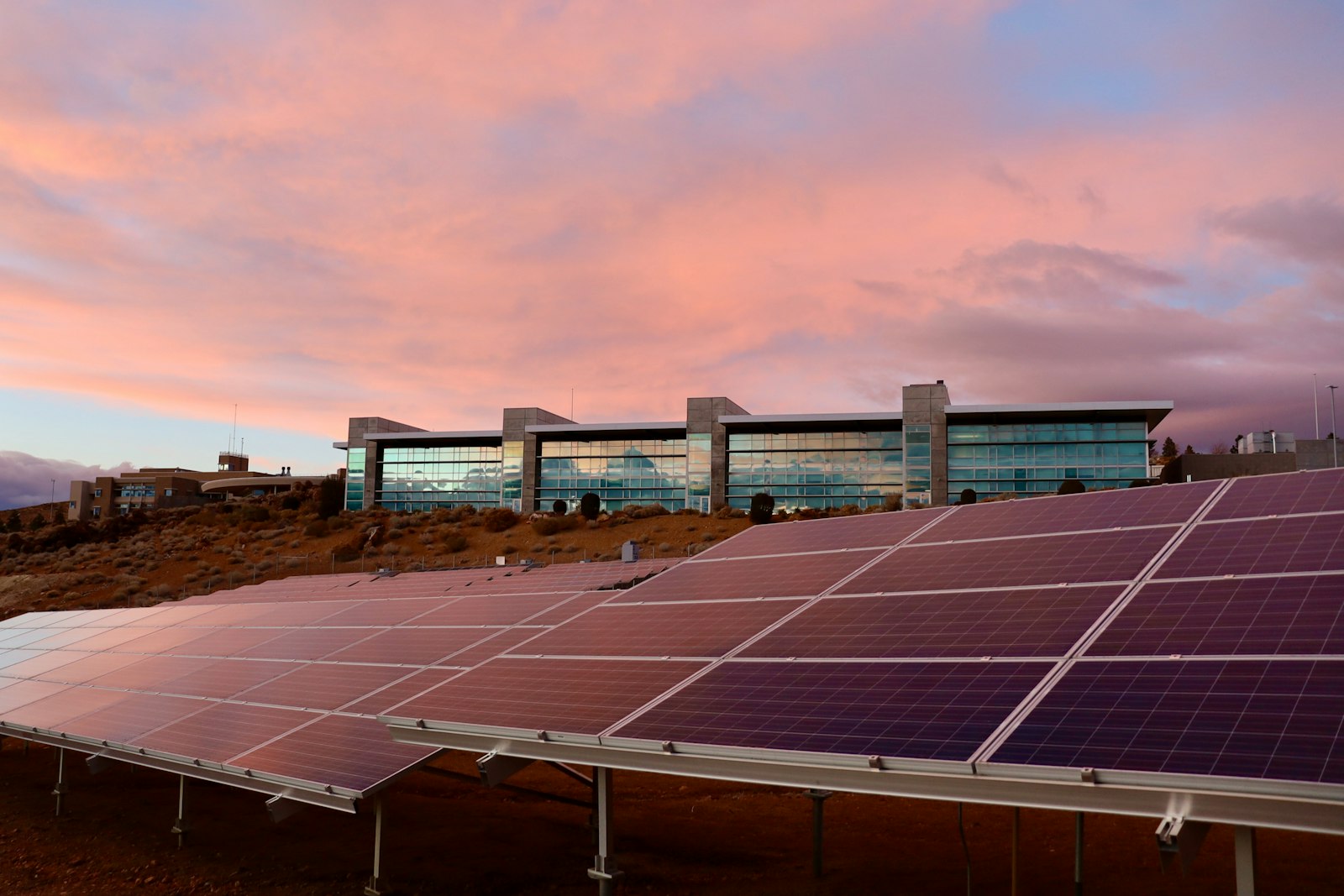 Paneles solares al atardecer delante de un edificio de oficinas