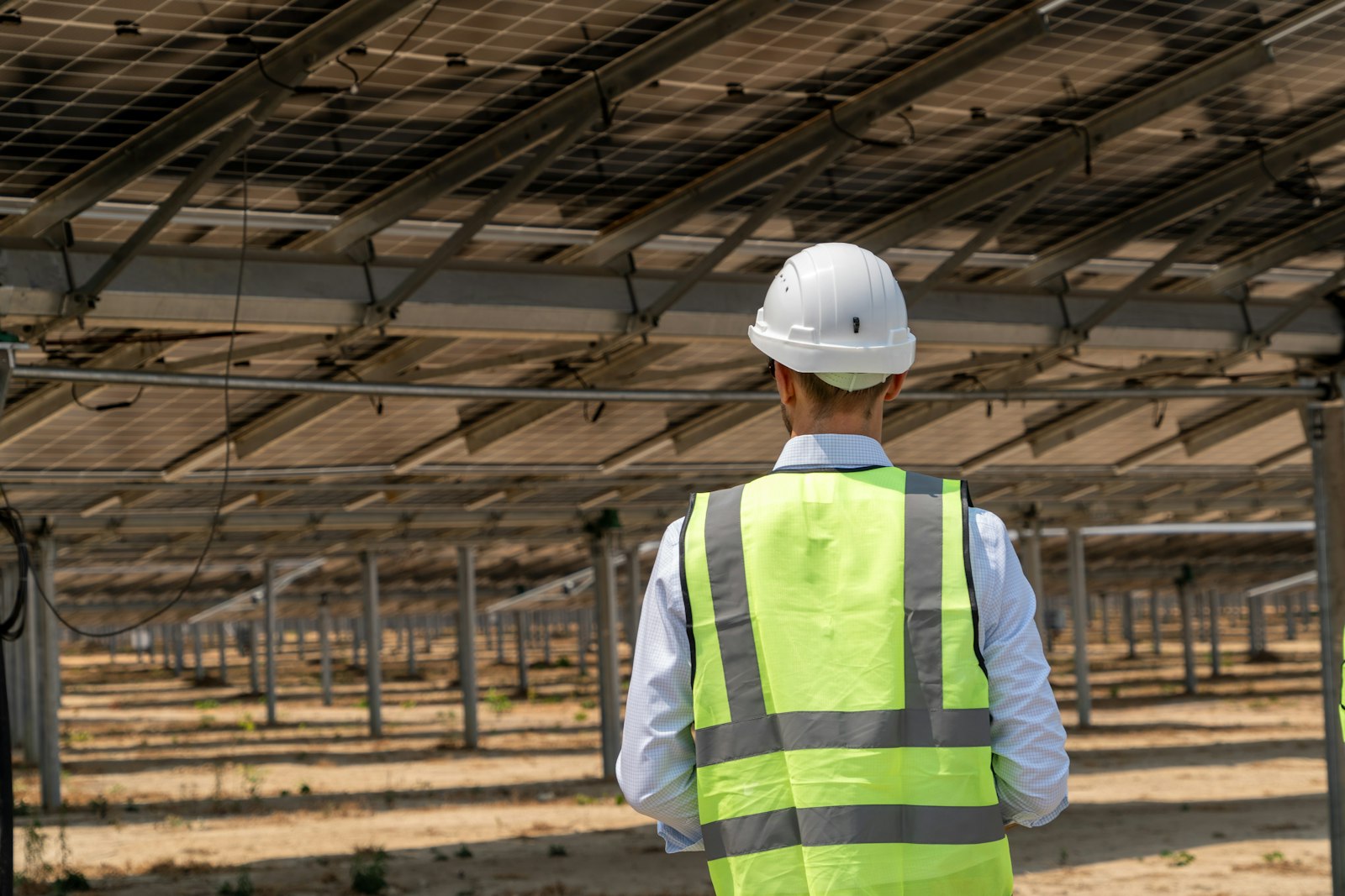 Técnico con casco y chaleco revisando una instalación solar